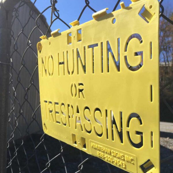 Molded For-ever Sign Yellow No Hunting or Trespassing installed on fence