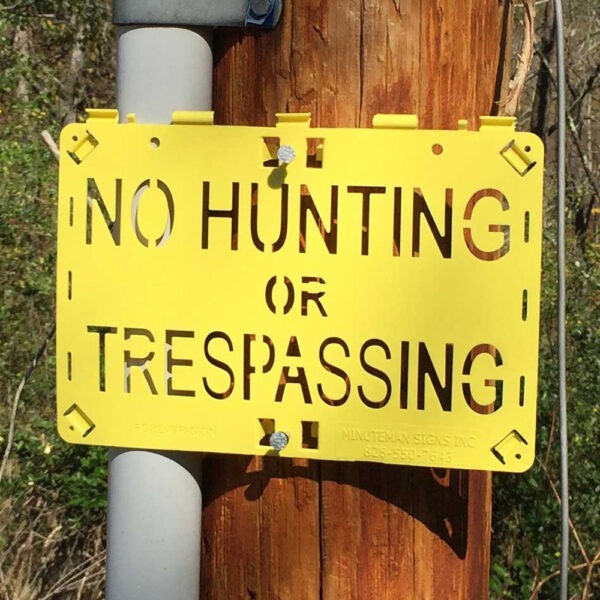 Molded Forever Sign Yellow No Hunting or Trespassing Sign installed on a post